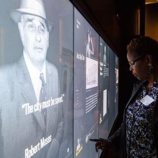 Photograph of an educator examining stories of New Yorkers from the 20th century in the World City gallery.