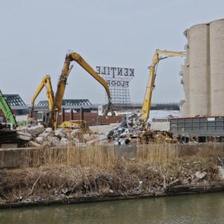 Excavators moving concrete in front of water 