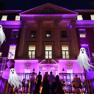 The facade of the Museum illuminated by purple lights, with Halloween ghosts flying above