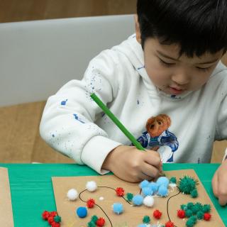 One child creating an artwork with colored pencils and collage.