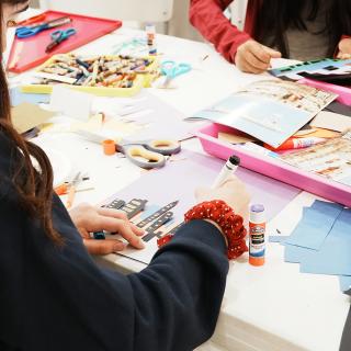 Two children creating an artwork with glue and cut paper.