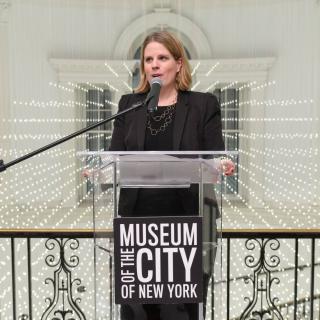 Image of curator Lilly Tuttle at clear podium with text logo "Museum of the City of New York"