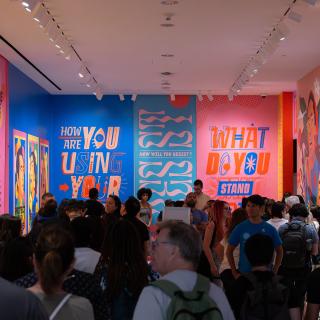 A crowd standing in a colorful gallery from the exhibition Activist New York.