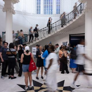 A crowd of people ascending a marble spiral staircase.