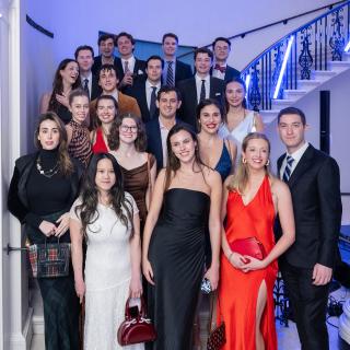 A group in cocktail attire stands on a spiral marble staircase