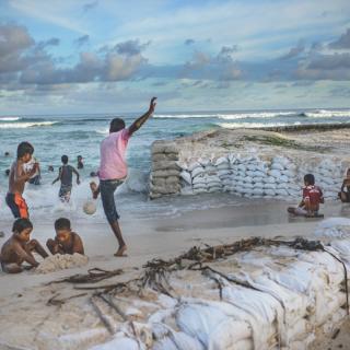 Children play on the beach where sandbags have been placed to try hold back the ocean at Temaiku, a vulnerable village on South Tarawa.
