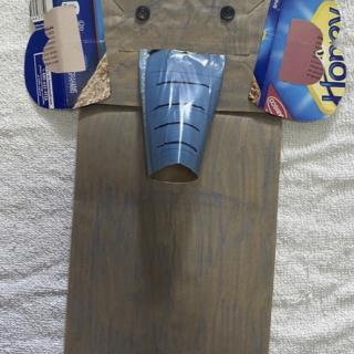 Brown paper lunch bag turned into a hand puppet designed to look like an elephant. It has two black buttons for eyes, two ears made from a blue cardboard food container, and a trunk made from a toilet paper roll covered in blue magazine paper. 