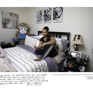Woman poses for photograph sitting on her bed