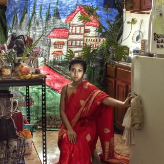 Artist sits in her kitchen with a painted background