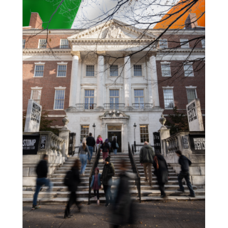 Visitors walking up the front steps of the Museum of the City of New York with flag of Ireland in background.