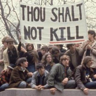 A group of people hold up protesting signs.