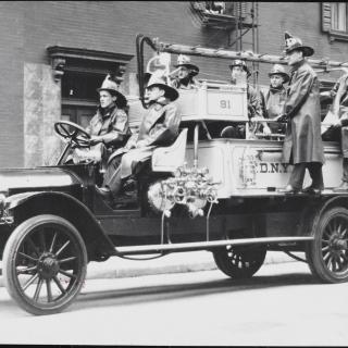 Firemen on a fire engine from the early 1900s