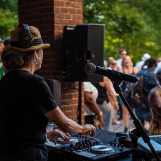 Image of DJ Misbeaviour on DJ controller and laptop with audience in background